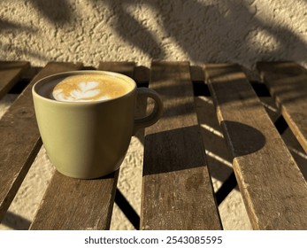 Warm cappuccino in a green ceramic cup on a sunlit wooden table - Powered by Shutterstock