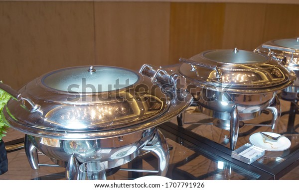 warm chafing\
dishes for heating food in hotel buffet banquet . Table with\
utensils and mirror boilers for meal . a closeup photo of dishware\
for a restaurant . Herbed\
rice