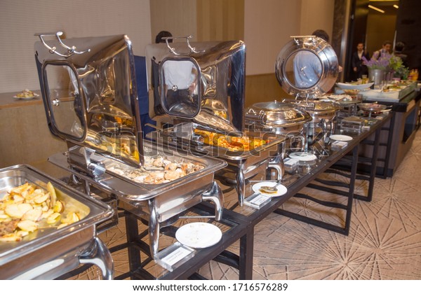 warm chafing dishes for heating food in hotel buffet\
banquet . Table with utensils and mirror boilers for meal . a\
closeup photo of dishware for a restaurant . Lamb Lamb stewed .\
Chicken breast .