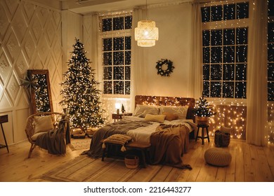 Warm Christmas evening in the interior of a bedroom with a double bed, a large Christmas tree, decorated with many lights of garlands. New Year's Eve, festive Christmas interior