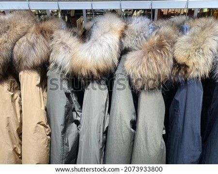 Warm coats with fur hoods  for autumn and winter hanging on clothes rail