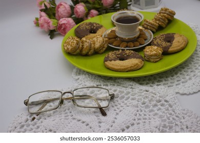 A warm coffee with almond garnish, assorted cookies on a green plate, and vintage glasses resting on a delicate crochet cloth. Pink roses add a soft touch. - Powered by Shutterstock