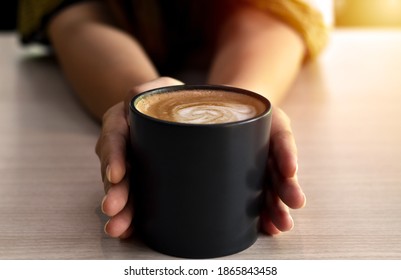 Warm coffee in a black mug with woman hand. - Shutterstock ID 1865843458