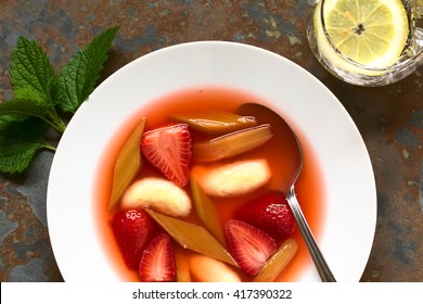 Warm Or Cold Fruit Soup Made Of Strawberry, Rhubarb And Semolina Dumplings Served In Soup Plate With Spoon, Photographed Overhead On Slate With Natural Light