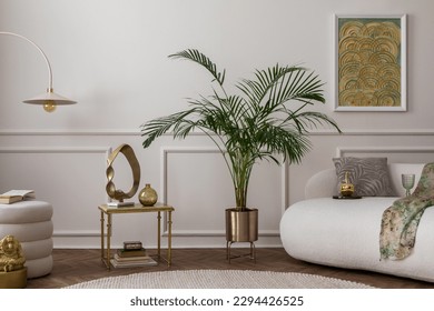 Warm composition of living room interior with boucle armchair, sofa, plant in gold pot, green pillows, round rug, stylish coffee table, wall with stucco and personal accessories. Home decor. Template.