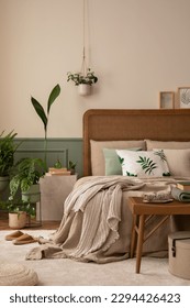 Warm and cozy bedroom interior with mock up poster frame, boho bed, beige bedding, green wall with stucco, books, brown slippers, plants in pots and personal accessories. Home decor. Template. - Shutterstock ID 2294426423
