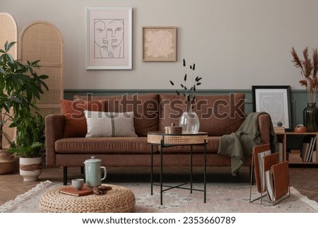 Warm and cozy composition of living room interior with mock up poster frame, brown sofa, beige rug, orange coffee table, wooden partition wall and personal accessories. Home decor. Template. 