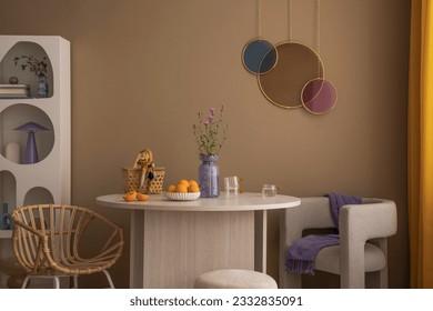 Warm and cozy living room interior with colorful ornament on wall, round table, gray armchair, modern rack, chair, orange curtain, brown wall, fruit and personal accessories. Home decor. Template.