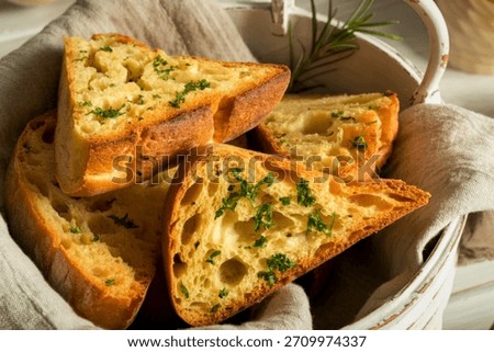 Warm, crusty garlic bread triangles, generously seasoned with herbs, are artfully arranged in a rustic white basket.