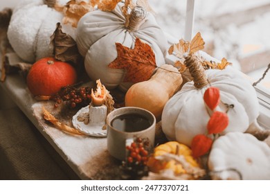 Warm cup of tea, pumpkins, autumn leaves, candle and woolen scarf on windowsill. Autumn hygge still life. Happy Thanksgiving. Hello fall - Powered by Shutterstock