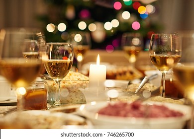 Warm Dining Table Full Of A Variety Of Delicious Festive Food And Wine In Home With A Christmas Tree In The Background