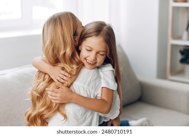 Warm embrace little girl hugging her mother on cozy couch in family living room - Powered by Shutterstock