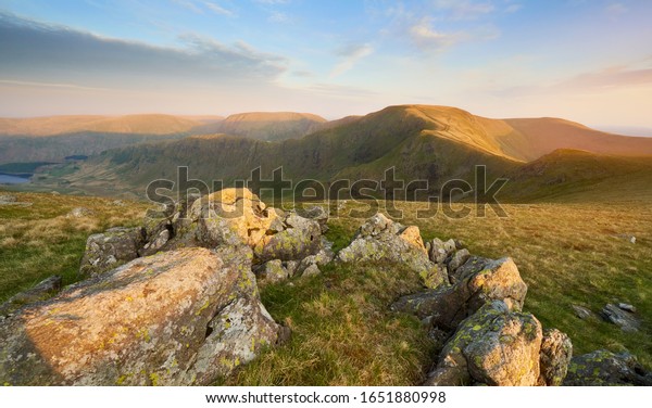The warm evening glow as sunset approaches over\
the summit of High Street with Mardale Ill Bell and Harter Fell to\
the left and Thronthwaite to the right. Rampsgill Head in the Lake\
District.