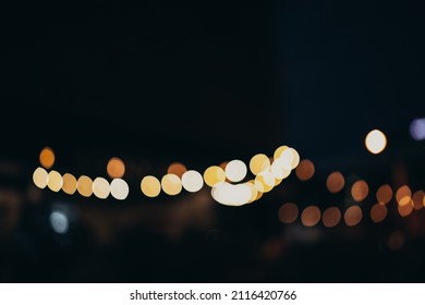 Warm Festive Bokeh Of String Lights Over An Outdoor Bar And Restaurant Patio At Twilight