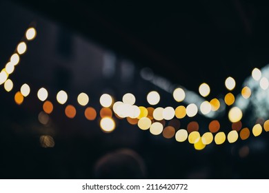 Warm Festive Bokeh Of String Lights Over An Outdoor Bar And Restaurant Patio At Twilight