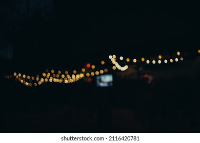 Warm Festive Bokeh Of String Lights Over An Outdoor Bar And Restaurant Patio At Twilight