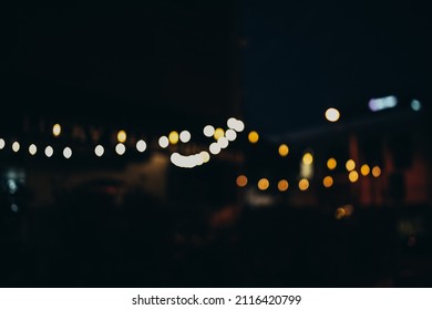 Warm Festive Bokeh Of String Lights Over An Outdoor Bar And Restaurant Patio At Twilight