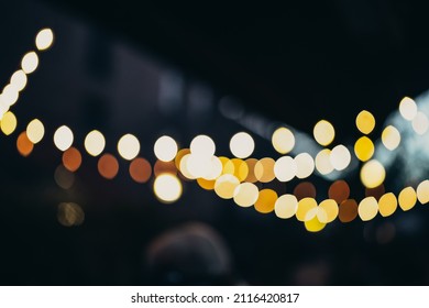 Warm Festive Bokeh Of String Lights Over An Outdoor Bar And Restaurant Patio At Twilight