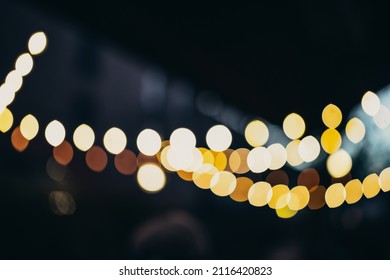 Warm Festive Bokeh Of String Lights Over An Outdoor Bar And Restaurant Patio At Twilight