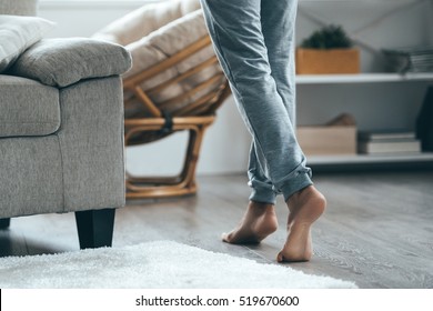 Warm floor concept. Close-up of female legs stepping by hardwood floor at home 