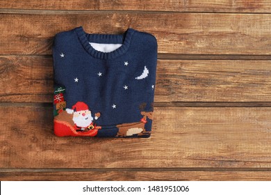 Warm Folded Christmas Sweater On Wooden Table, Top View. Space For Text