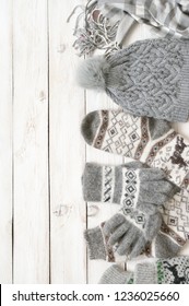 Warm Grey Woolen Knitwear: Socks, Gloves, Pom Hat And Scarf On White Rustic Wood Background. Winter Cozy Still Life. 