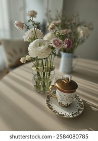 A warm and inviting tea time setting bathed in afternoon sunlight, featuring a delicate ranunculus floral arrangement and a cup of coffee. This high-resolution image captures a serene and elegant
