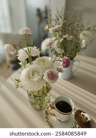 A warm and inviting tea time setting bathed in afternoon sunlight, featuring a delicate ranunculus floral arrangement and a cup of coffee. This high-resolution image captures a serene and elegant atmo