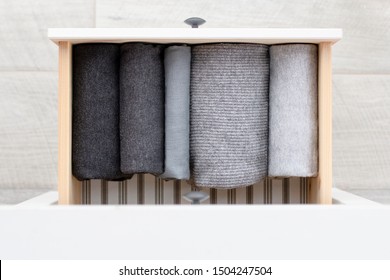 Warm Knitted Clothes In Shades Of Gray Neatly Folded In A Straight Row In A Drawer, Top View