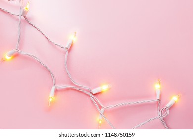 Warm  light garlands on pink background, festive decorations.  Flat lay, top view
