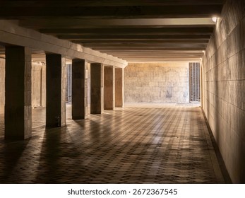 Warm light illuminating an empty underground passage, highlighting concrete columns and a tiled floor, creates a mysterious and evocative atmosphere filled with intrigue and depth