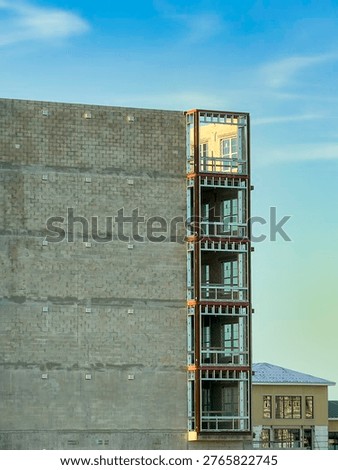 Warm light from setting sun illuminates top corner unit of a multistory senior living facility under construction in southwest Florida. Concepts of height, distinction, and synchronism.