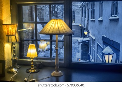 Warm lighting coming out from beautiful retro table lamps, against cold lighting from window in a winter evening.