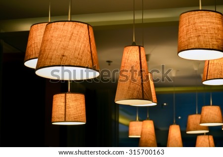 Warm lighting coming out from beautiful lamps on ceiling , while taking a hot cup of coffee in a trendy cafe with nice environment, Selective focus on central lamp