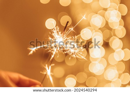 Warm lights as abstract bokeh made from Christmas lights with sparkling Sparkler. Holiday concept, blur bokeh, postcard concept.