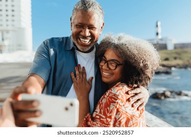 A warm moment between an Afro-Brazilian couple taking a selfie near the Farol da Barra lighthouse in Salvador, Bahia. The iconic backdrop symbolizes the cultural significance of the region. - Powered by Shutterstock