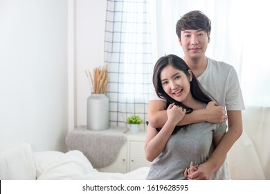 Warm Moment. Young Asian Couple Man Hugging Woman From Behind In Bed Room