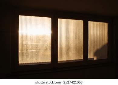 Warm morning sunlight filters through a frosted window, casting soft glows and shadows in apartment building. A serene depiction of peaceful beginnings and tranquil home environments. - Powered by Shutterstock