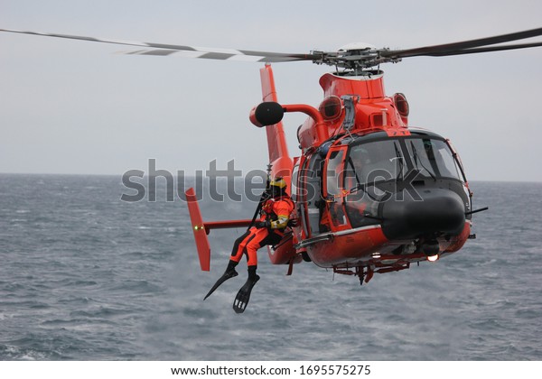 Warm orange helicopter with a survival swimmer\
hanging out, neutral\
backround.