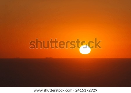 Warm orange sunset over the sea horizon with ship traveling towards the sun, Portugal