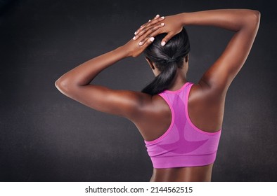 Warm Up Is Part Of The Routine. Rearview Studio Shot Of A Fit Woman Stretching Against A Black Background.