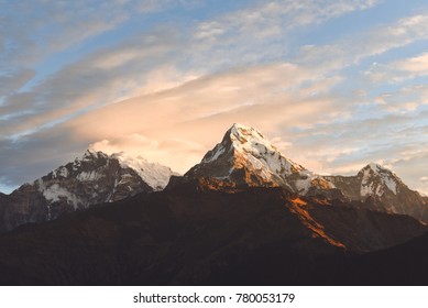 Warm pink and orange sunrise light over Annapurna mountain range with beautiful clouds, view from Poon hill in Himalayas, Nepal