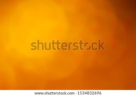 Warm reds and oranges create a bold and bright bokeh abstract background from sunlight reflecting off blown out of focus petals