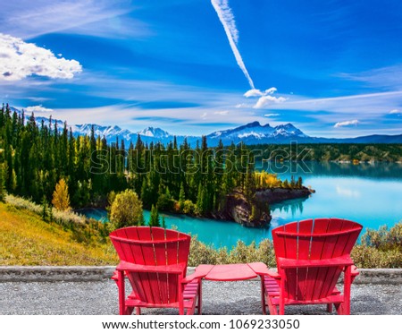 Warm September in the mountains of Canada. Two red comfortable loungers by the Abraham lake with turquoise water. Concept of ecological and active tourism