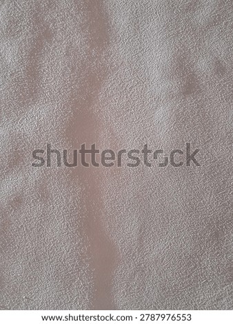 Warm side sunlight revealing the bumpy surface, rough plaster texture, and imperfections of a beige painted indoor wall.