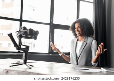 With a warm smile and open hands, businesswoman conveys a sense of approachability and friendliness, inviting interaction in an educational vlog or webinar from her office, recording vlog or classes - Powered by Shutterstock