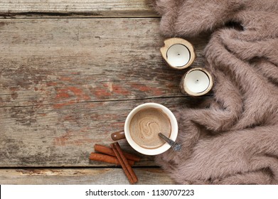 Warm Soft Blanket, Cup Of Hot Chocolate, Candles And Cinnamon Sticks On Old Rustic Wood Background. Cozy Still Life. Top View Point.