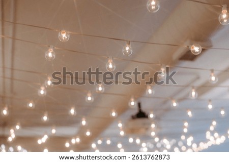 Warm string lights create a cozy, intimate ambiance inside a wedding venue during the evening reception, perfect for rustic or modern celebrations.