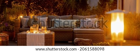 Warm summer night in the garden with trendy furniture, lights, lanterns and candles