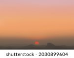 Warm summer sunset over the mountains. The sun is about to set and is visible in an almost perfect circumference, in a vibrant reddish hue.